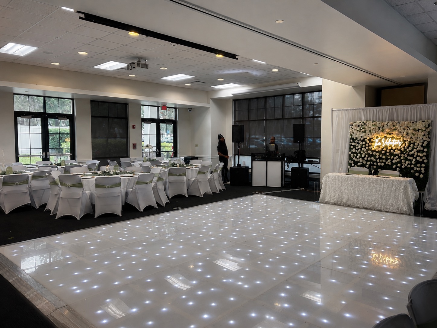White LED dance floor reception with a flower wall backdrop, produced by Rental Setups
